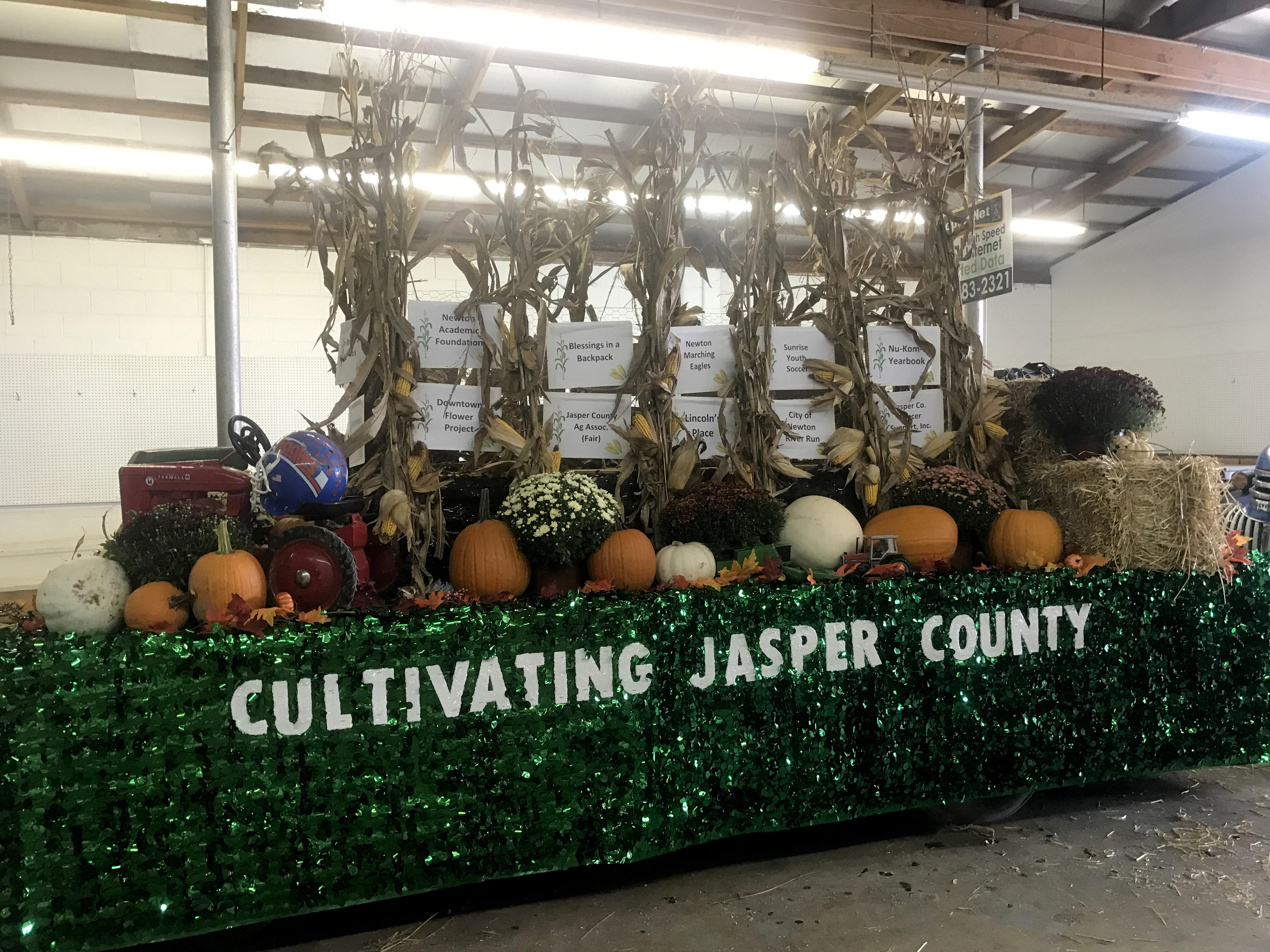Fall themed float with green float skirting, pumpkins, gourds, corn stalks