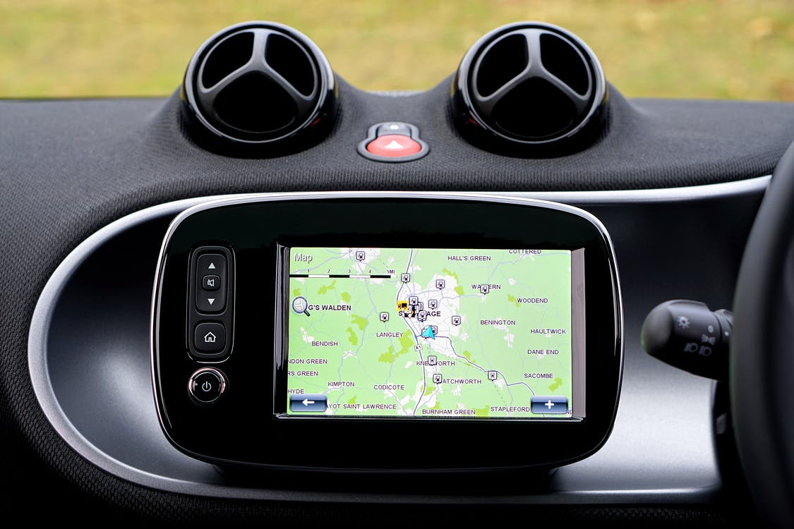 Car dashboard with GPS showing map and pinged locations.