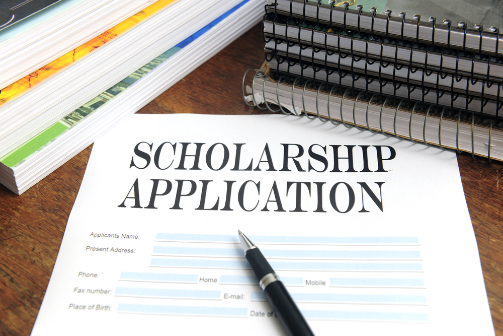 scholarship application with ink pen on a desk surrounded by books